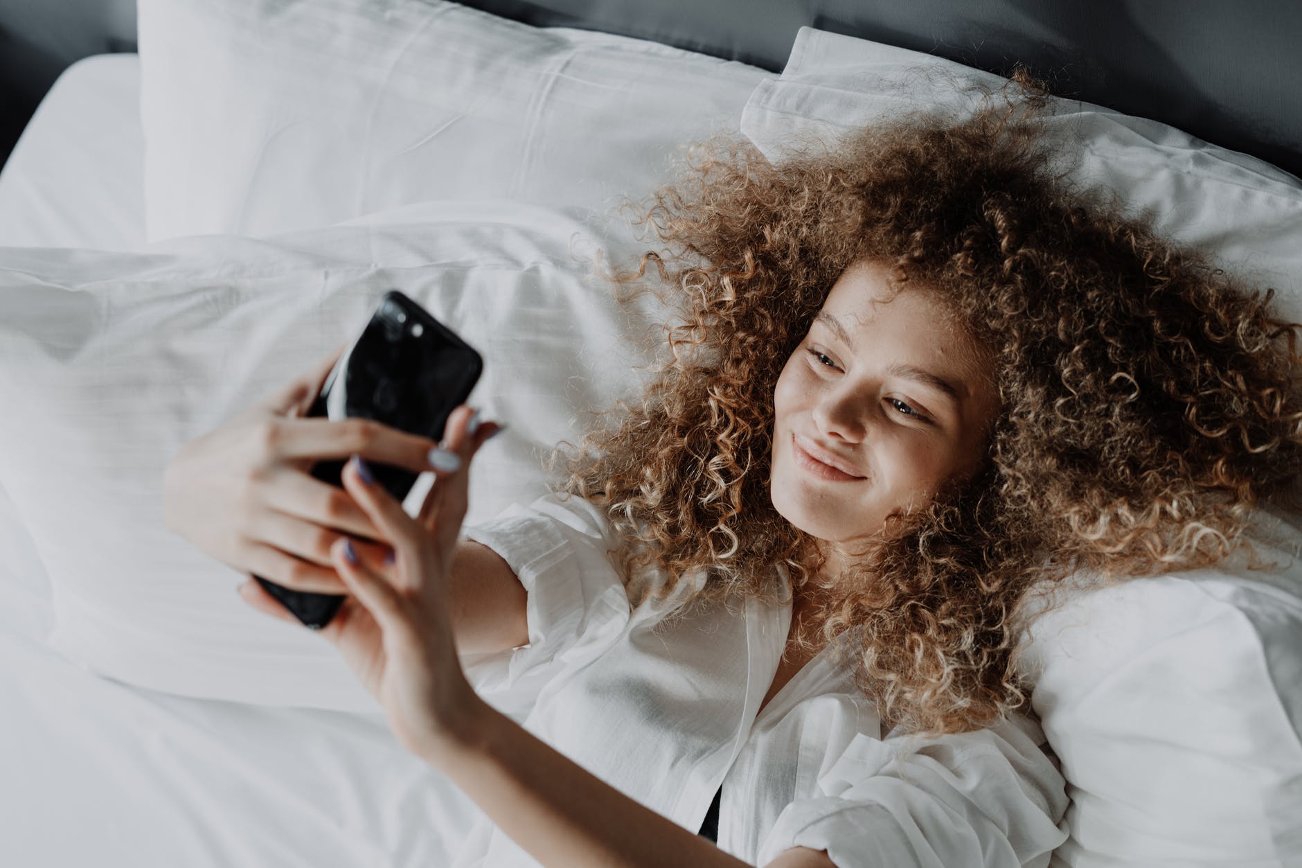 woman in white button up shirt lying on bed